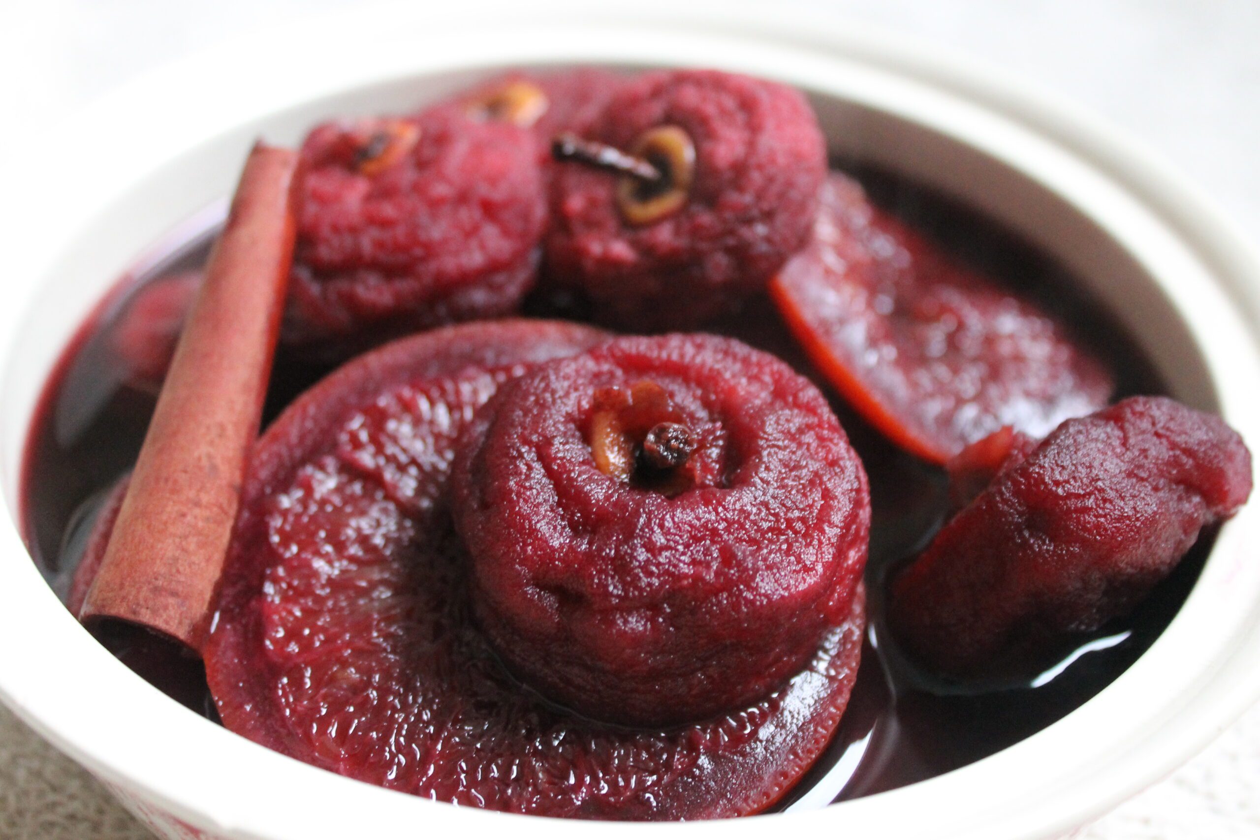 bowl of dried apples soaked in red wine so they are blood red in colour, and studded with cinnamon sticks and cloves