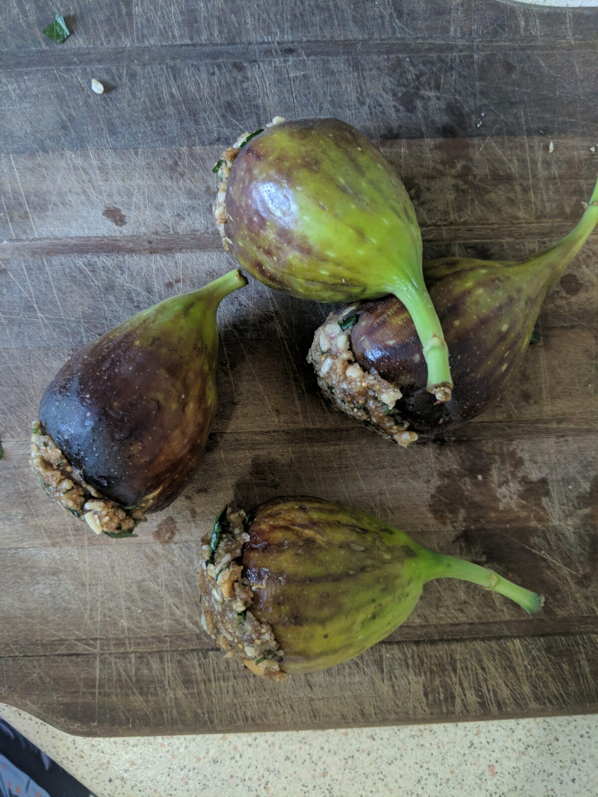 four uncooked, stuffed figs on a wooden board